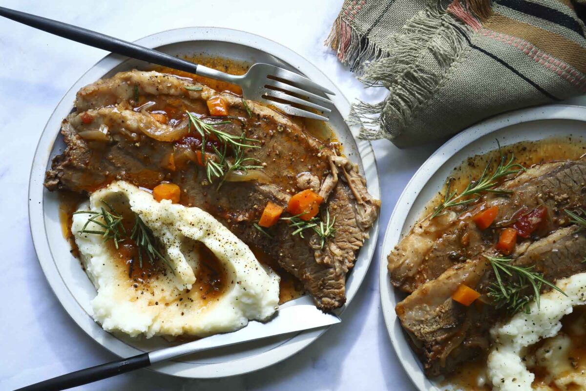 Sliced beef brisket on a plate with mashed potatoes.