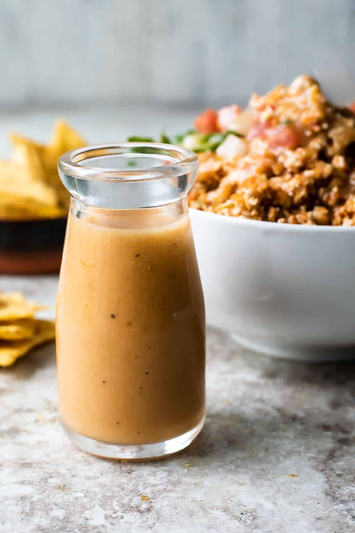 A bottle of Chipotle honey vinaigrette in front of a Chipotle sofritas burrito bowl.