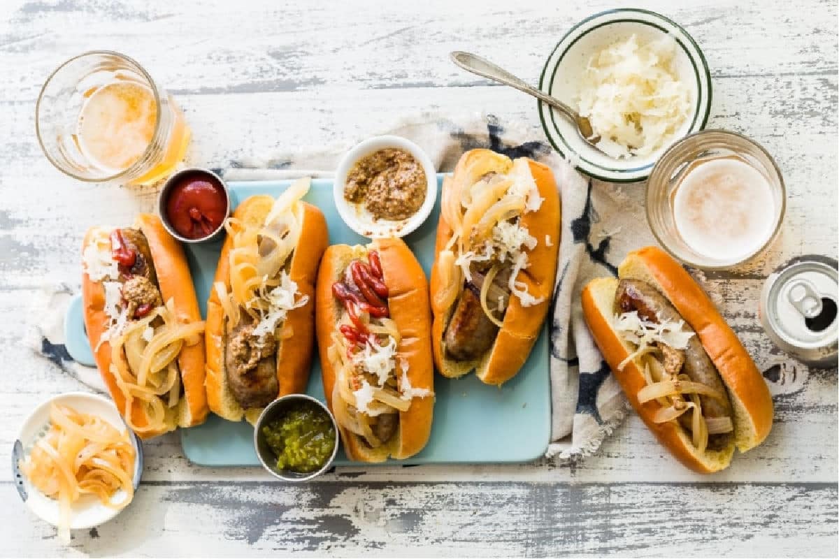 Beer brats with relish, onions, and ketchup on buns.