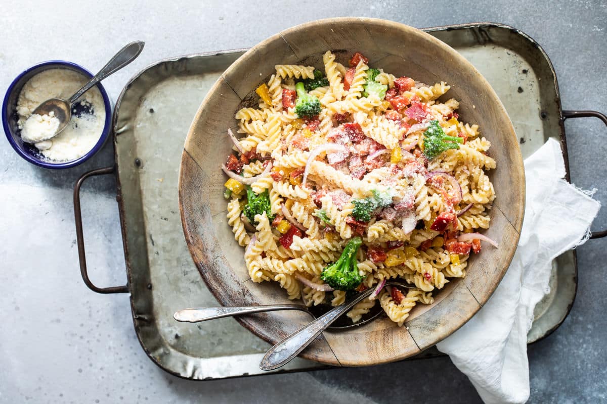 A bowl of cold pasta salad with broccoli and peppers.