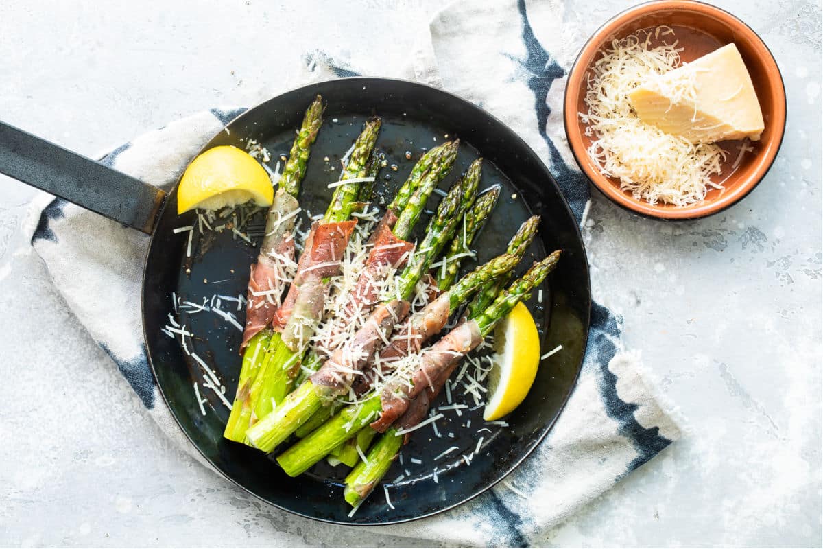 Prosciutto wrapped asparagus in a black pan.