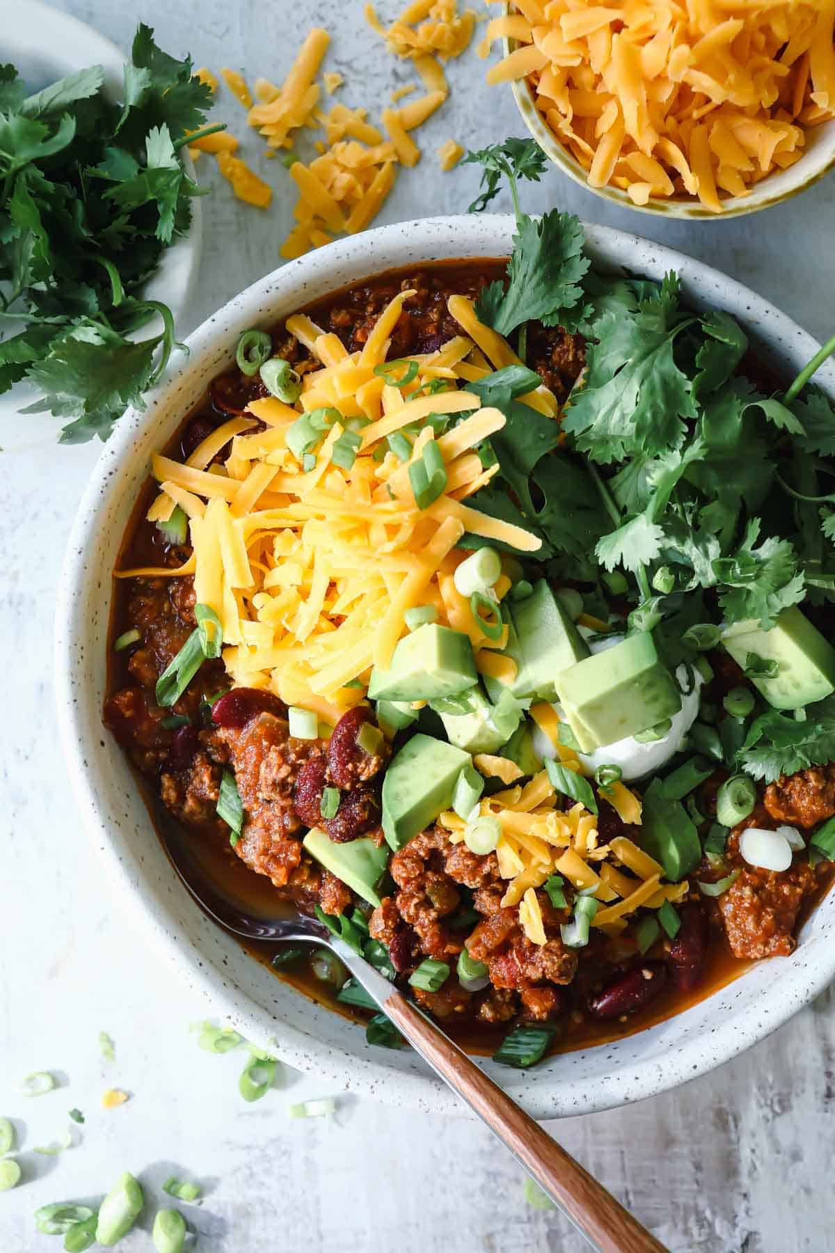 A bowl of turkey chili with toppings.