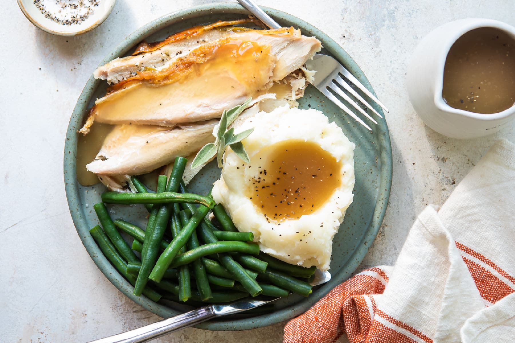 A plate of food for Friendsgiving: turkey breast, mashed potatoes, and green beans.