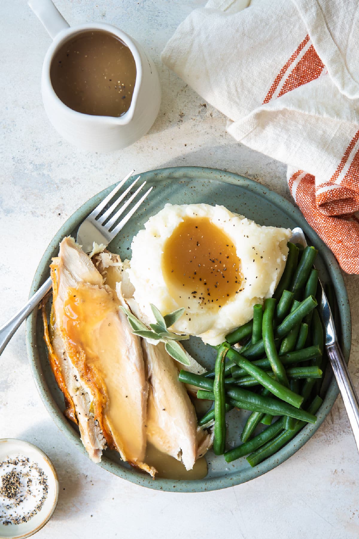 A plate of food for Friendsgiving: turkey breast, mashed potatoes, and green beans.