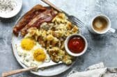 A plate of sunny-side up eggs, hashbrowns, bacon and ketchup.