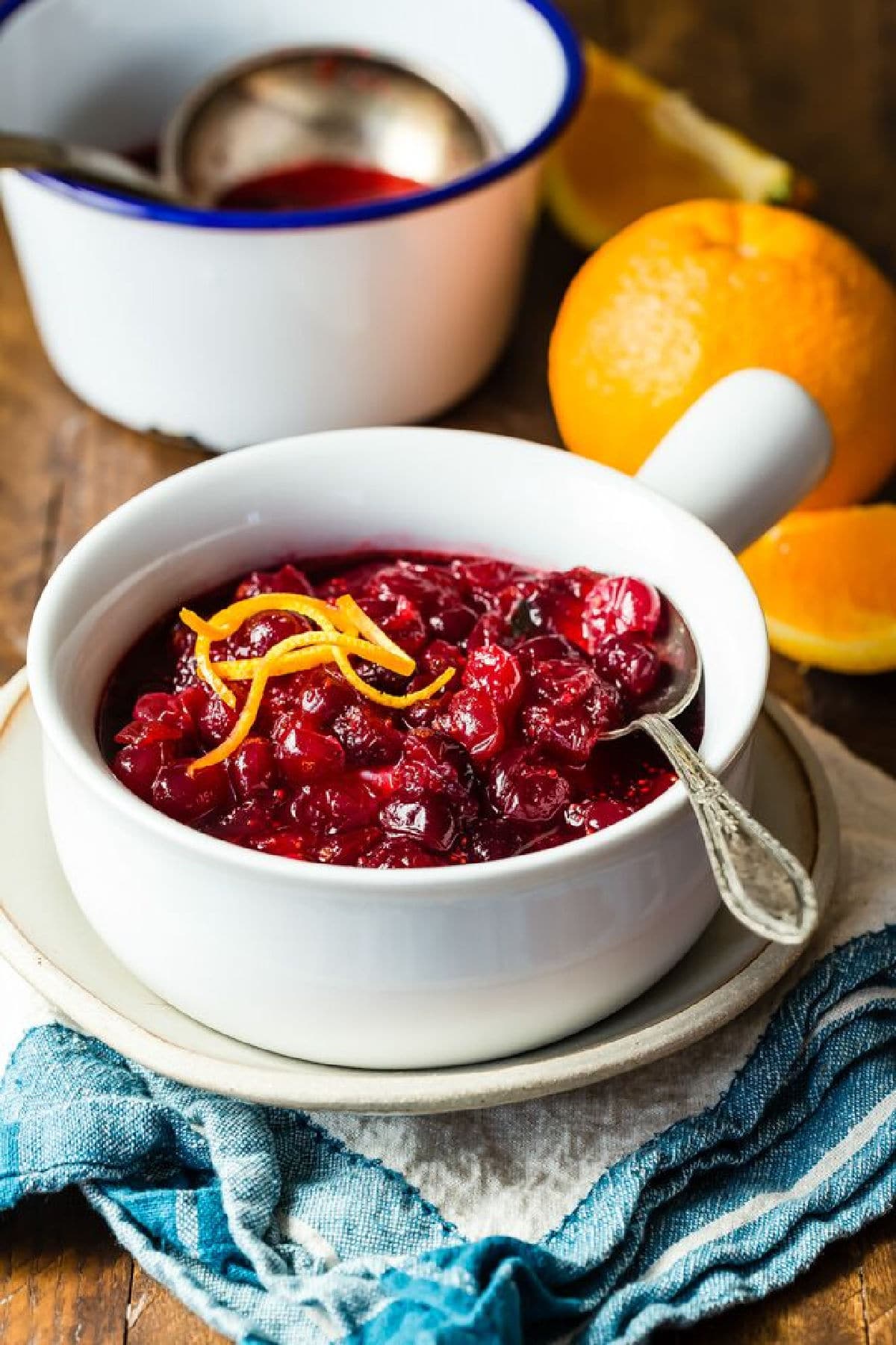 A bowl of cranberry sauce with some curls of orange zest on top.