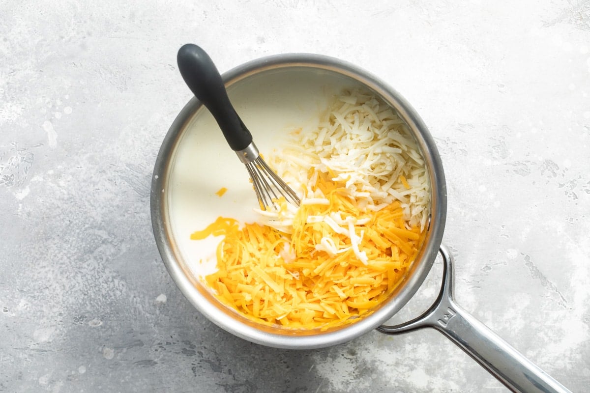 Adding cheese to a blonde roux to make cheese sauce.