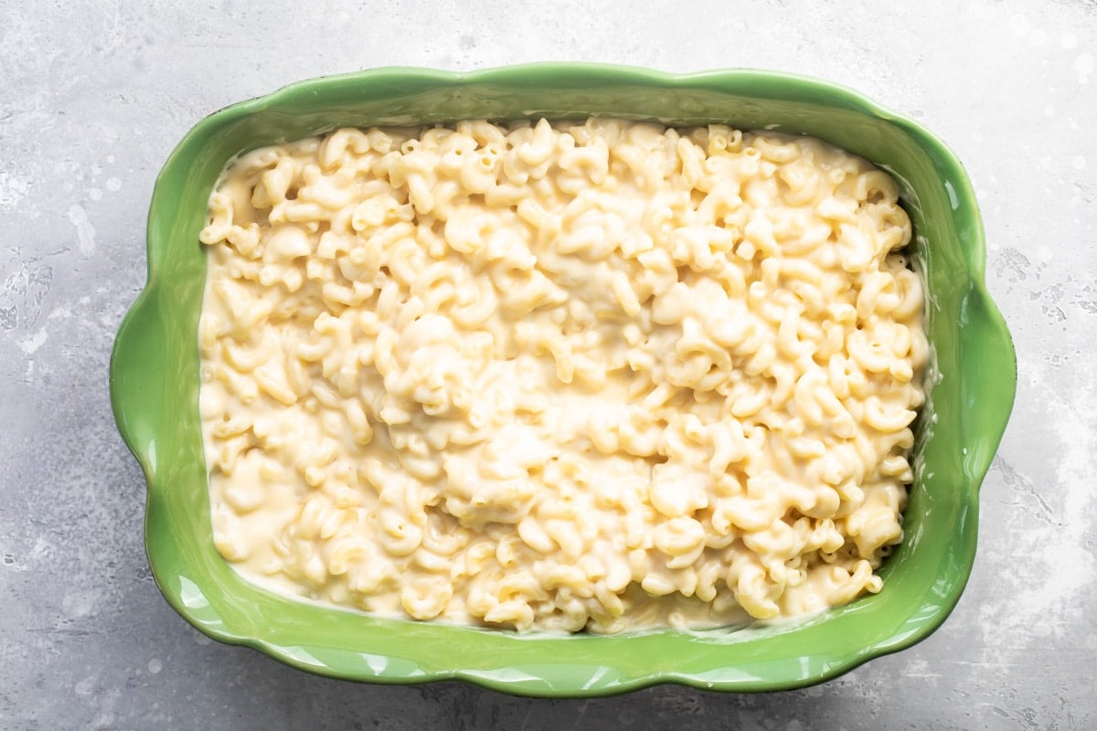 A green casserole dish full of mac and cheese.
