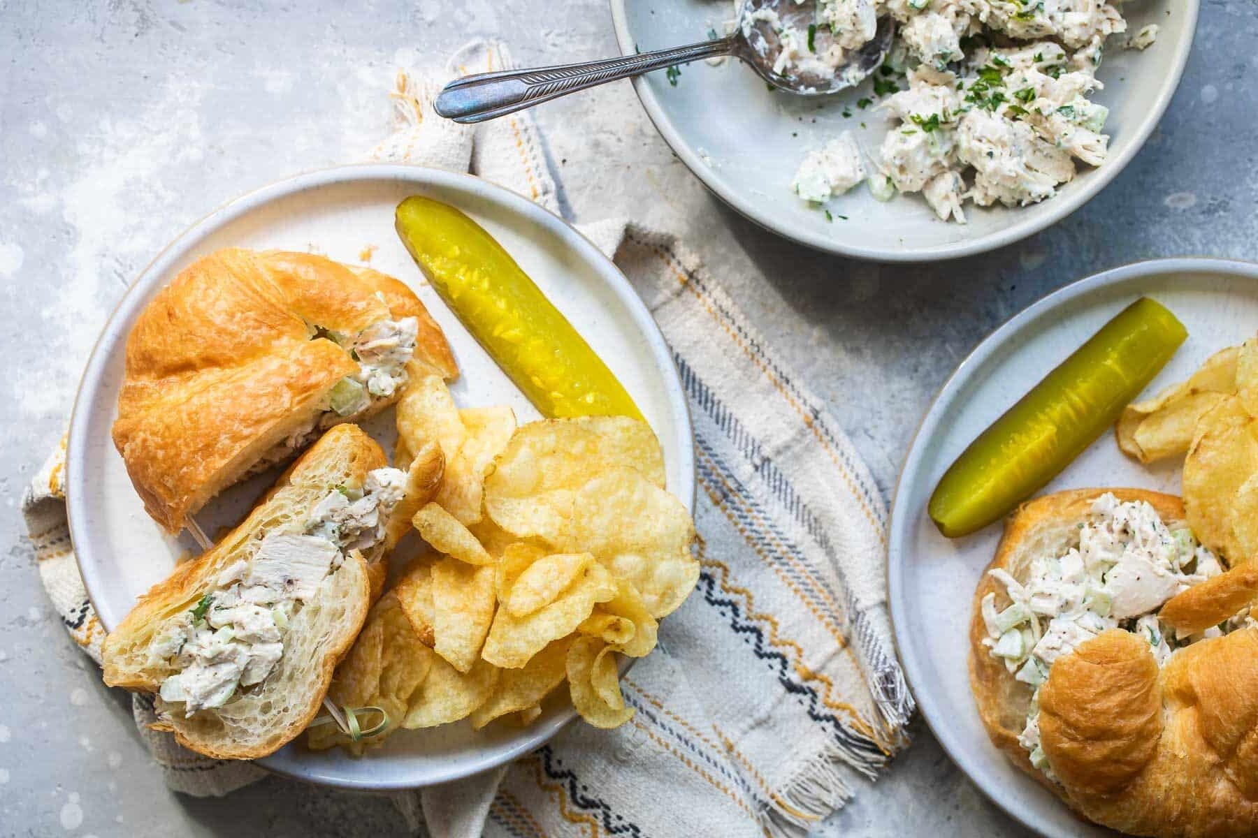 Turkey salad on croissants with chips and pickles.