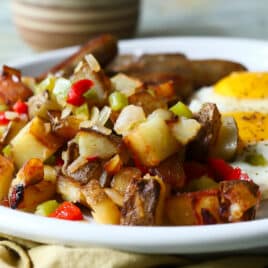 A plate of fried eggs with sausages and potatoes o'brien.
