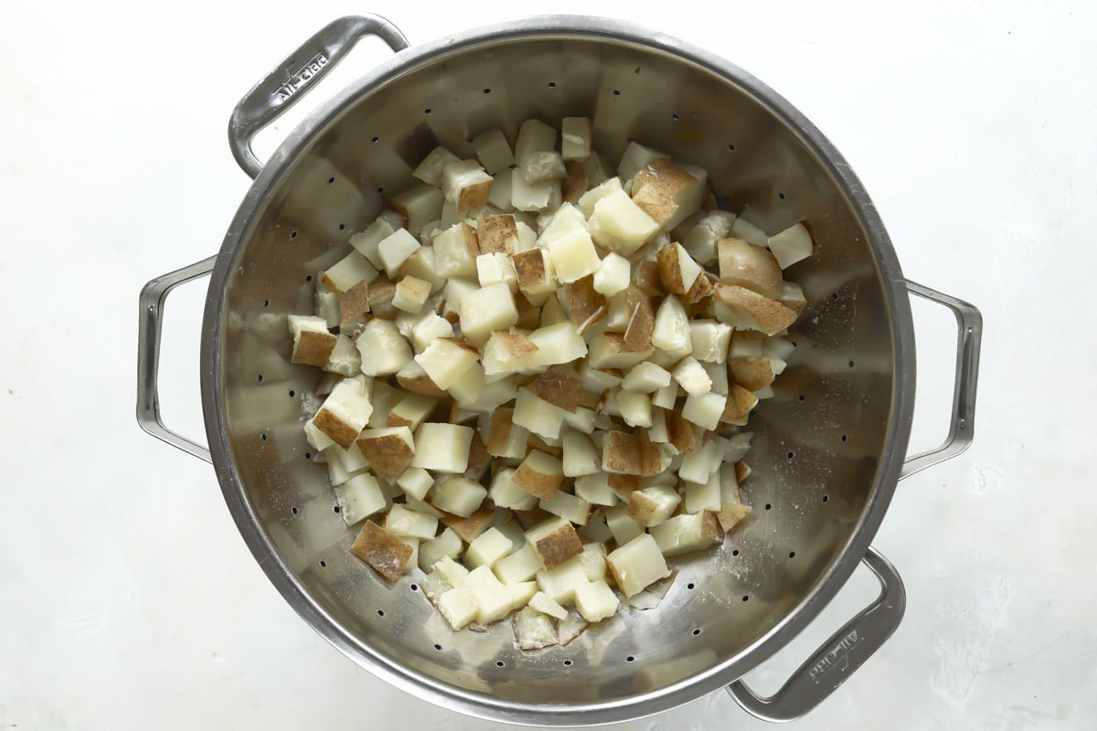 Par-boiled potatoes draining in a colander.