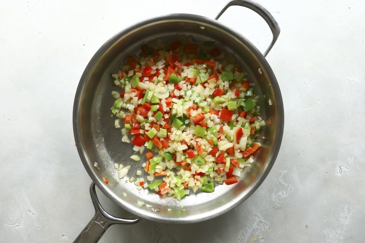 Peppers and onions in a skillet to cook.