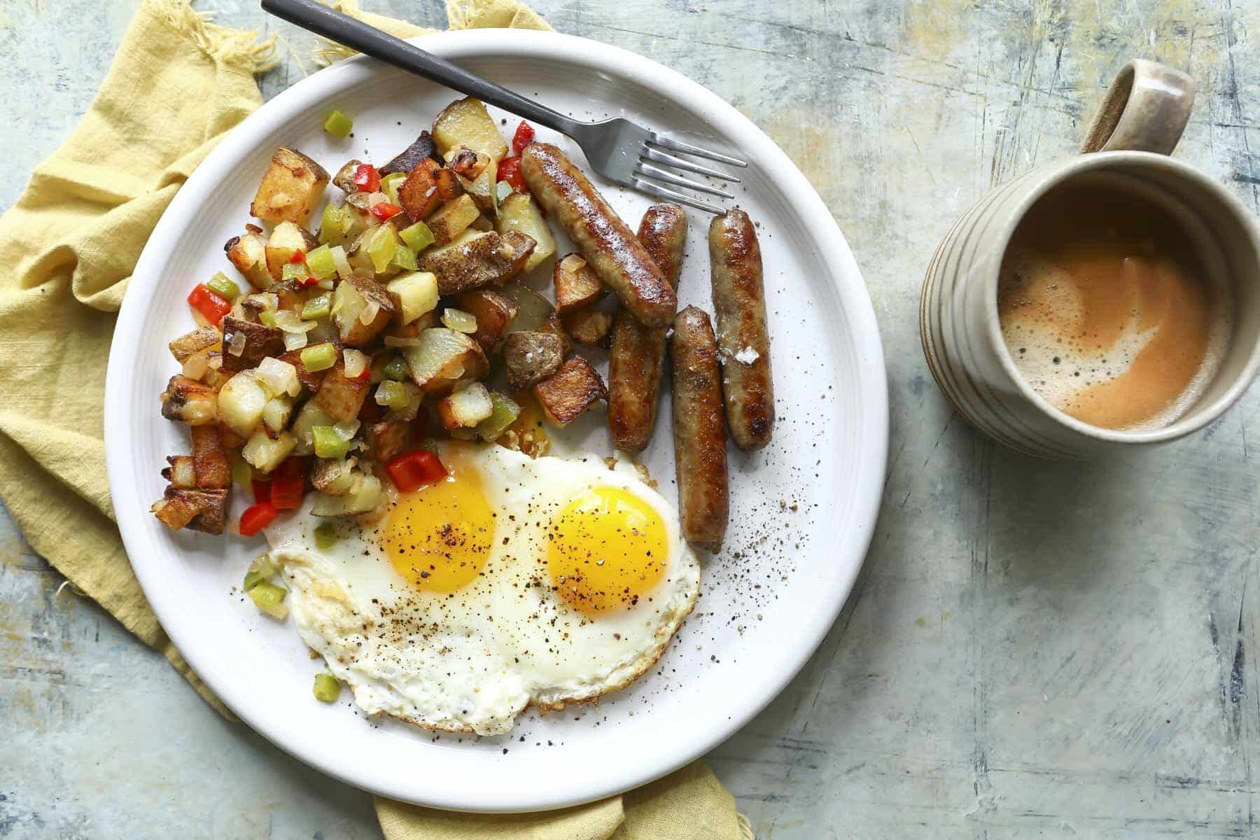 A plate of fried eggs with sausages and potatoes o'brien.