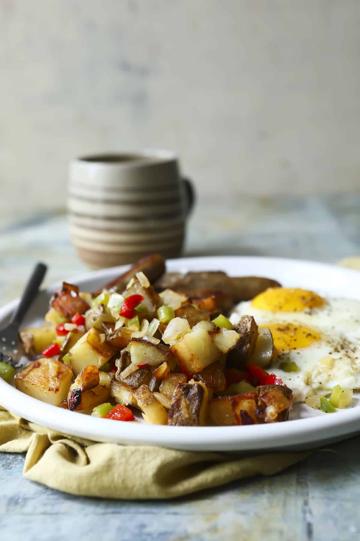 A plate of fried eggs with sausages and potatoes o'brien.