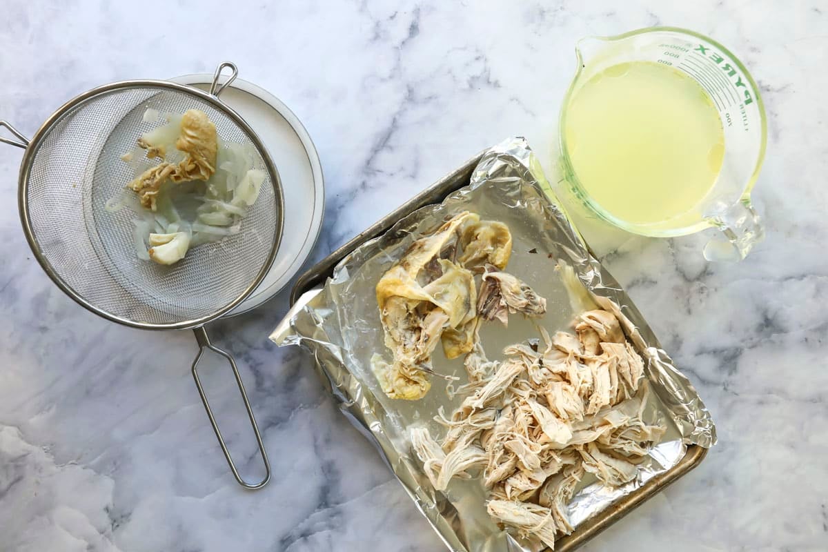 Separating chicken from the skin and bones on a sheet tray.