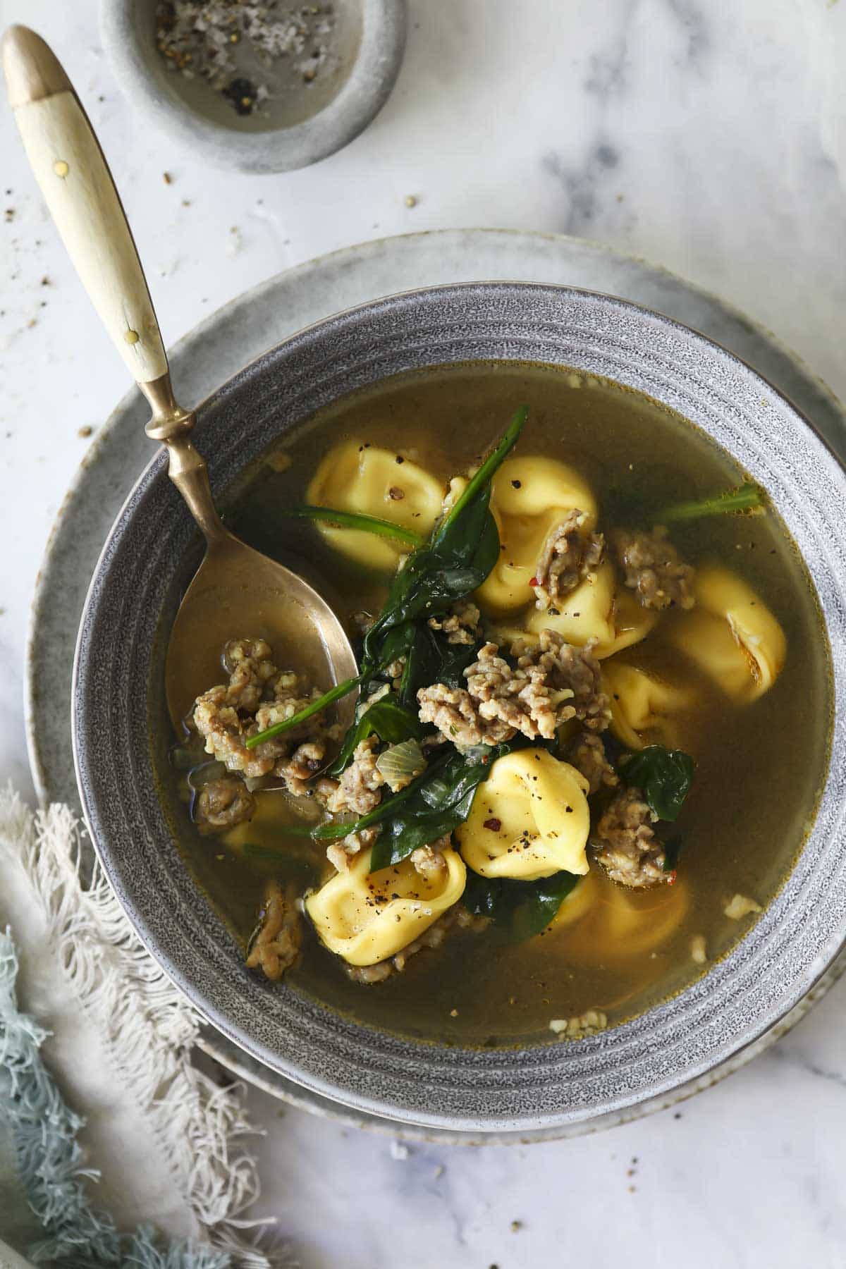 A bowl of sausage tortellini soup.