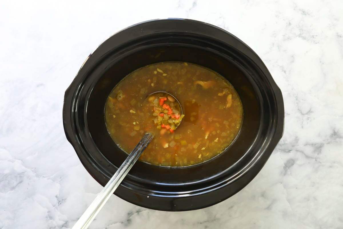 A slow cooker full of pasta and bean soup.