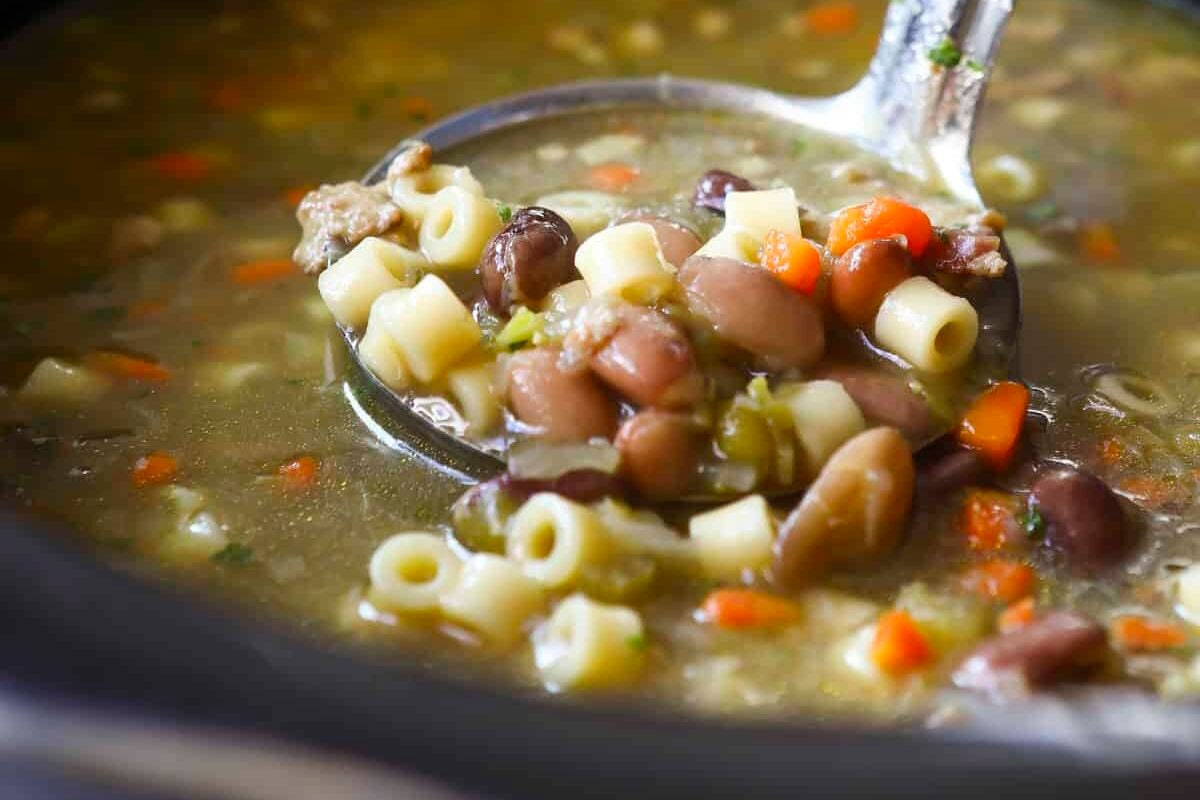 A slow cooker full of pasta and bean soup.