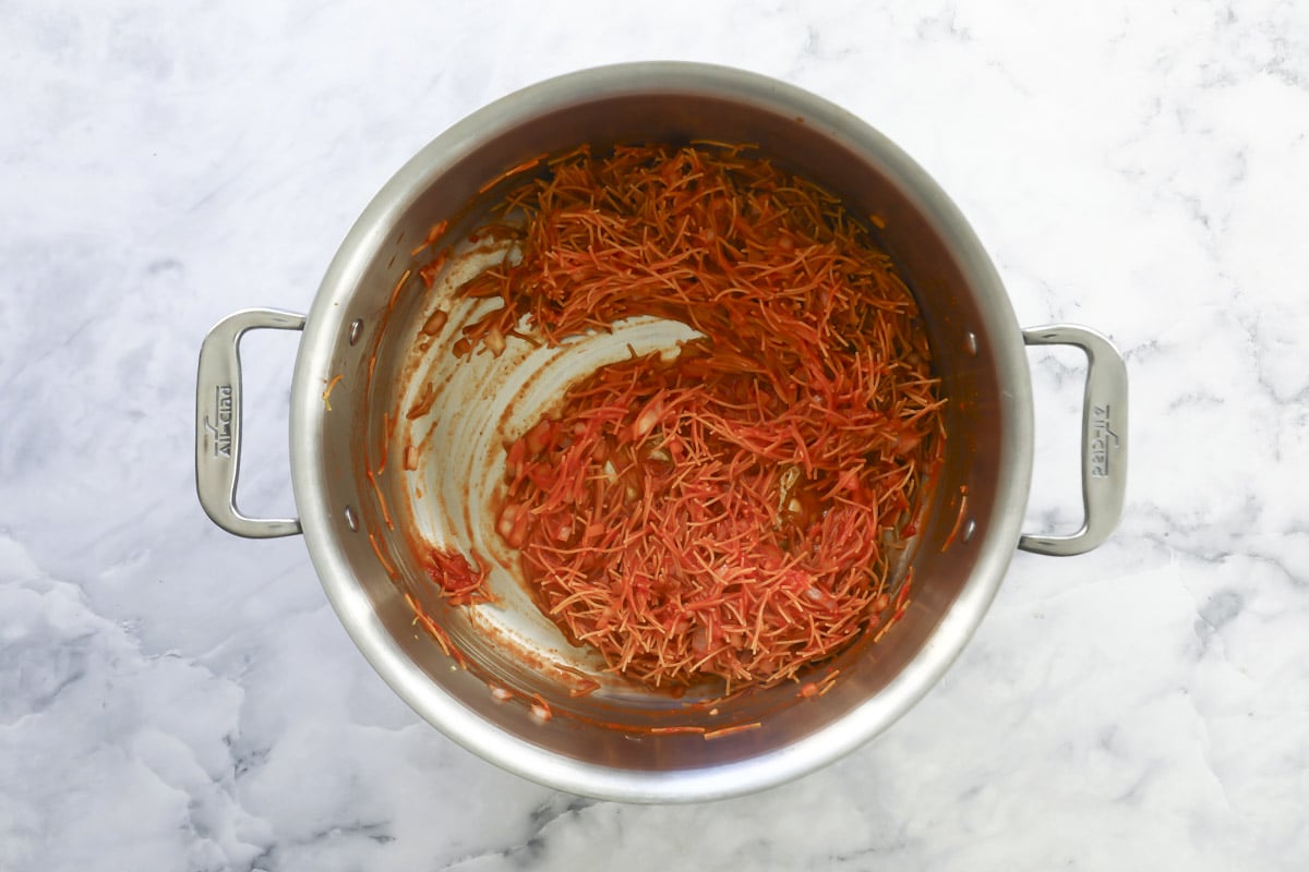 Adding tomatoes to fideo pasta for sopa de fideo.