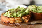 A slice of toast slathered with mashed avocado and sprinkled with red chili flakes.