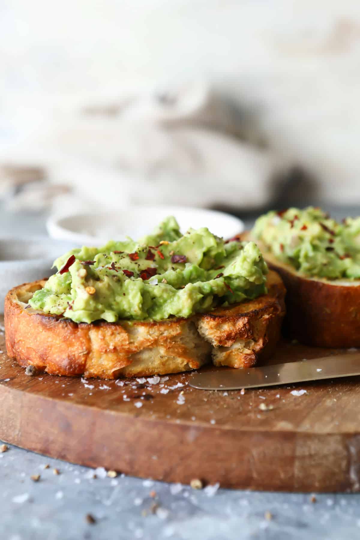 A slice of toast slathered with mashed avocado and sprinkled with red chili flakes.