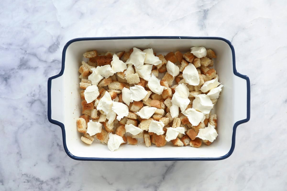Bread cubes in the bottom of a baking dish.