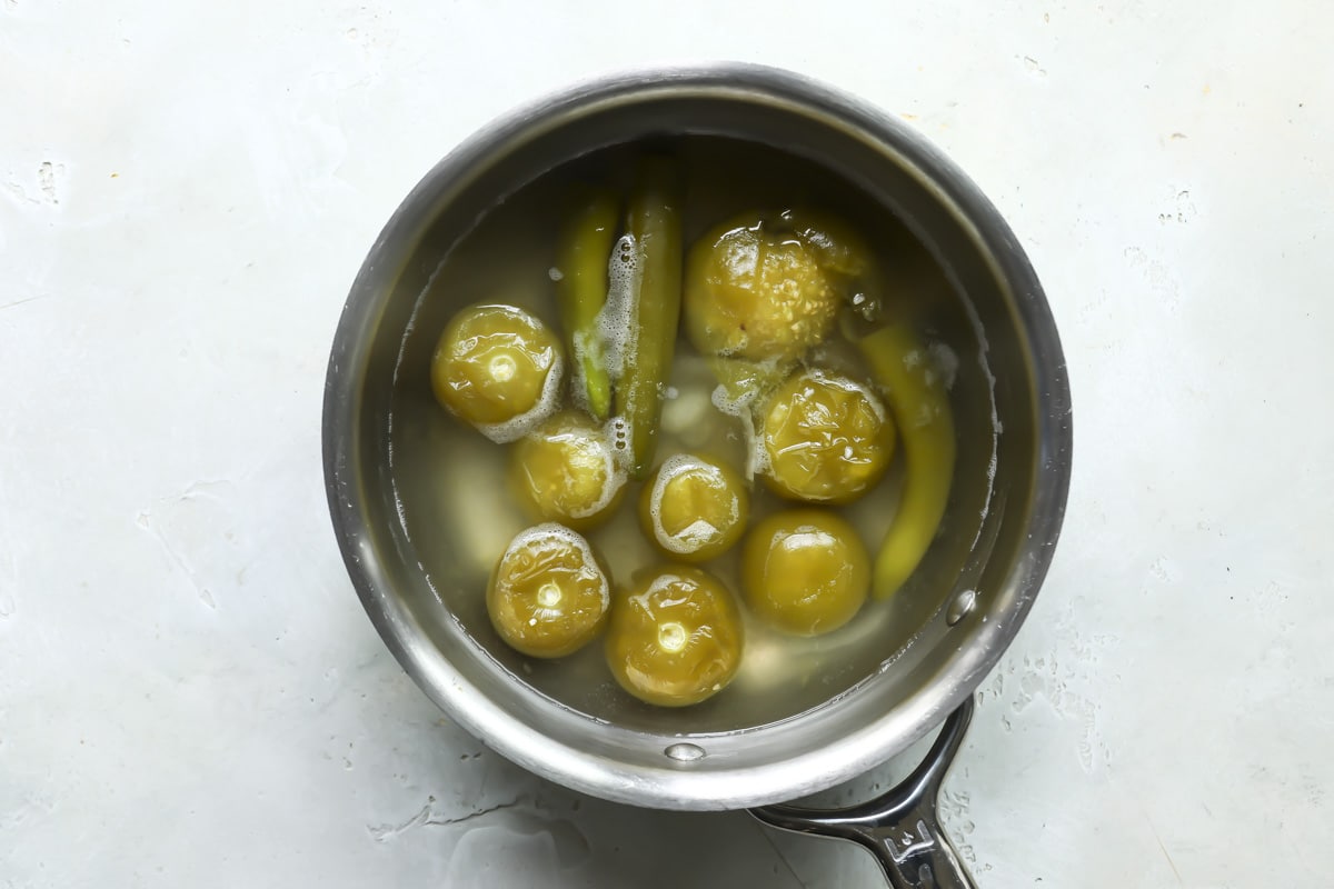 Boiled tomatillos, serranos, onions, and garlic in a pot with water for salsa verde.