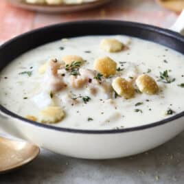 A bowl of clam chowder with oyster crackers on top.