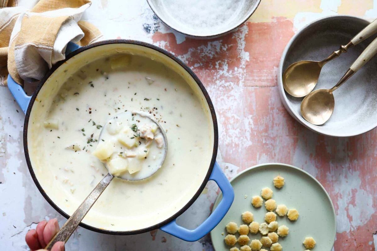 A pot of clam chowder with a ladle holding some soup.