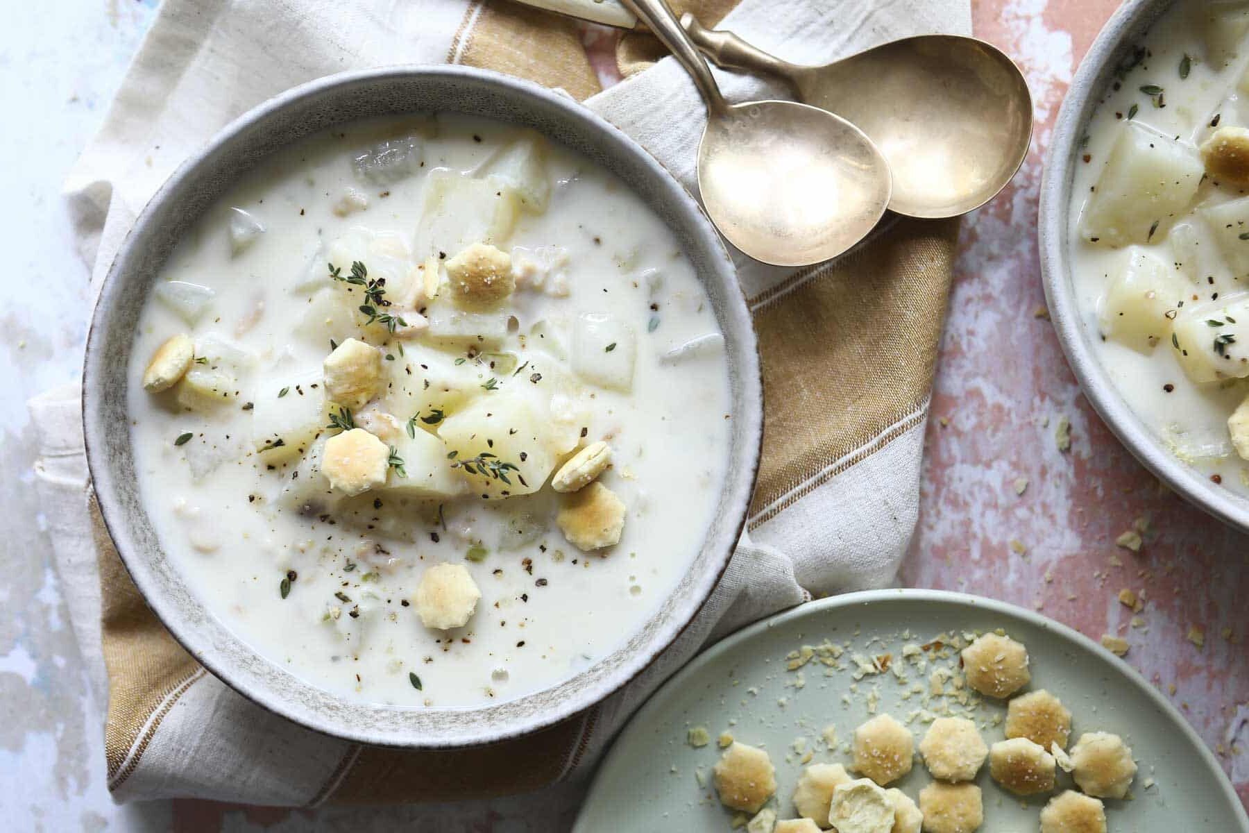 A bowl of clam chowder with oyster crackers on top.
