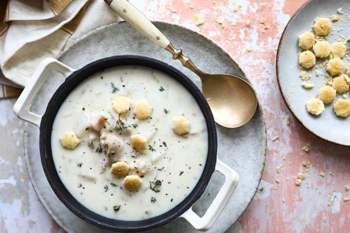 A bowl of clam chowder with oyster crackers on top.