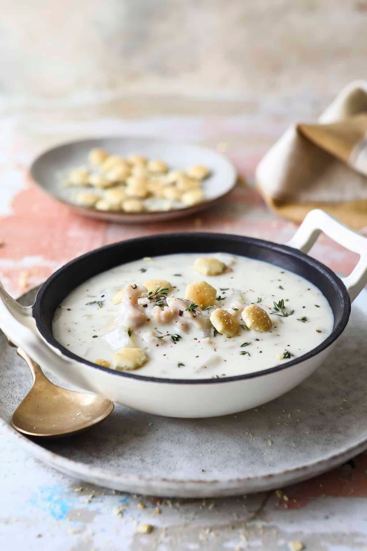 A bowl of clam chowder with oyster crackers on top.